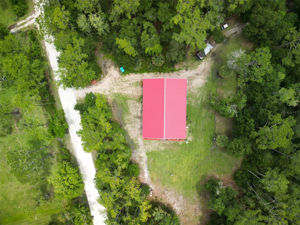 An aerial view shows a rectangular building with a red metal roof surrounded by trees — 425 WESTERN ROAD, NEW SMYRNA BEACH, FL