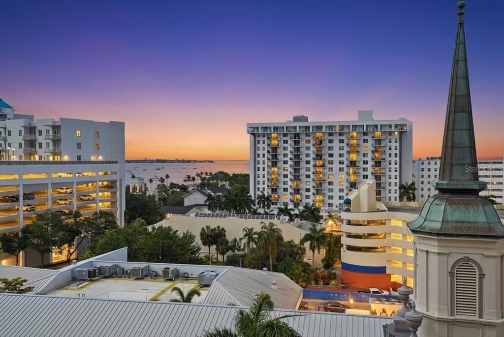 An elevated view of a city skyline featuring a church steeple and nearby high-rise buildings — 111 S PINEAPPLE AVENUE UNIT 714, SARASOTA, FL