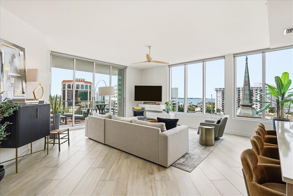 A modern living room features a sectional sofa, large windows, and views of a steeple — 111 S PINEAPPLE AVENUE UNIT 714, SARASOTA, FL