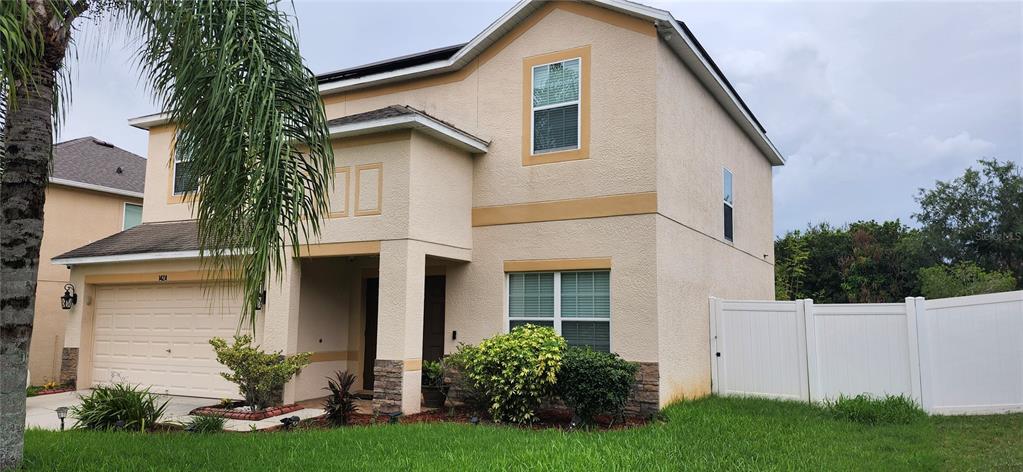 A two-story tan stucco house with a two-car garage, solar panels, and a palm tree — 1424 MAIN STREET, VALRICO, FL