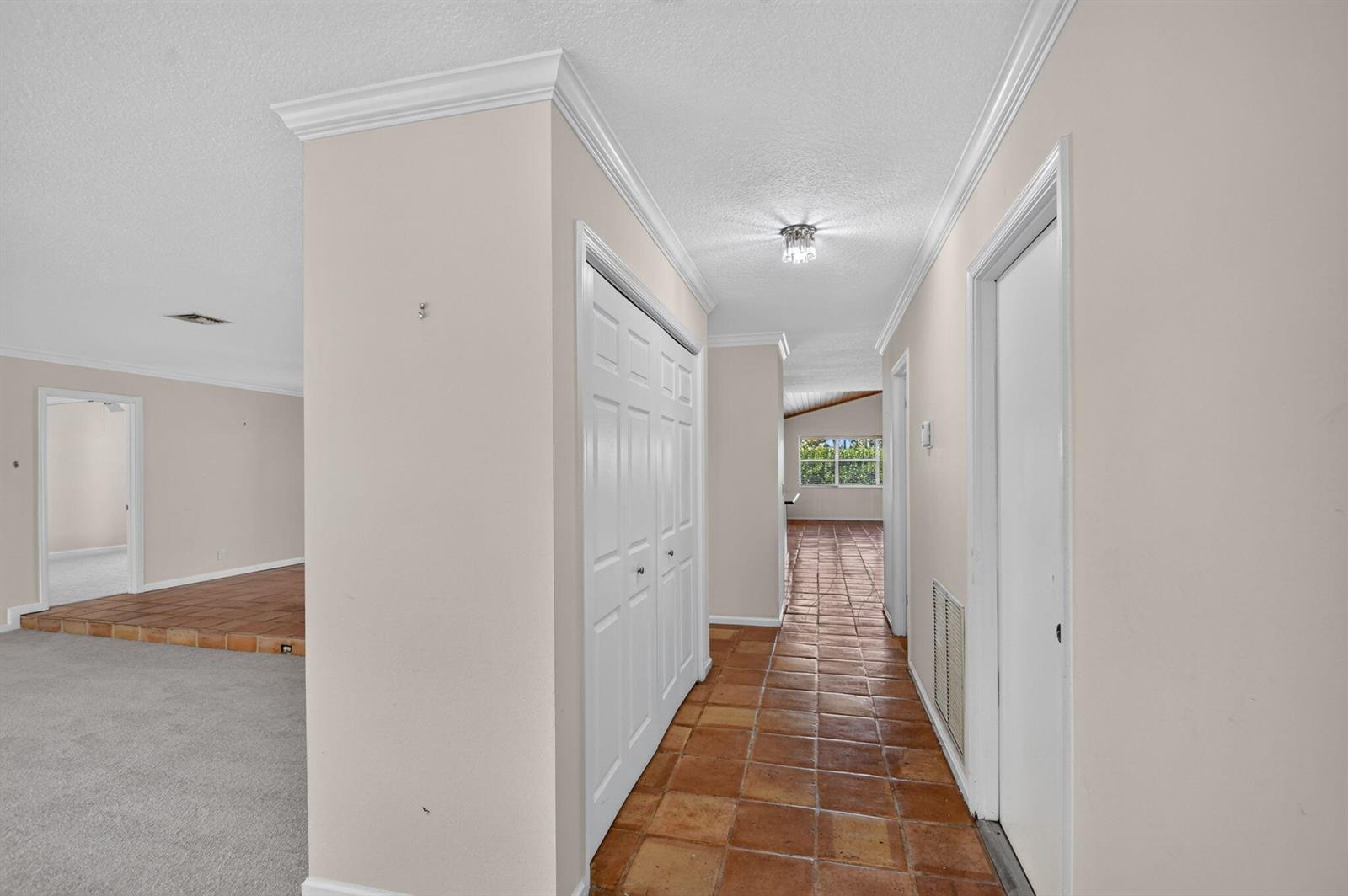 A hallway with terracotta tile flooring leads past a white closet to a bright room — 2400 SW 23rd Cranbrook Drive, Boynton Beach FL 33436, BOYNTON BEACH, FL