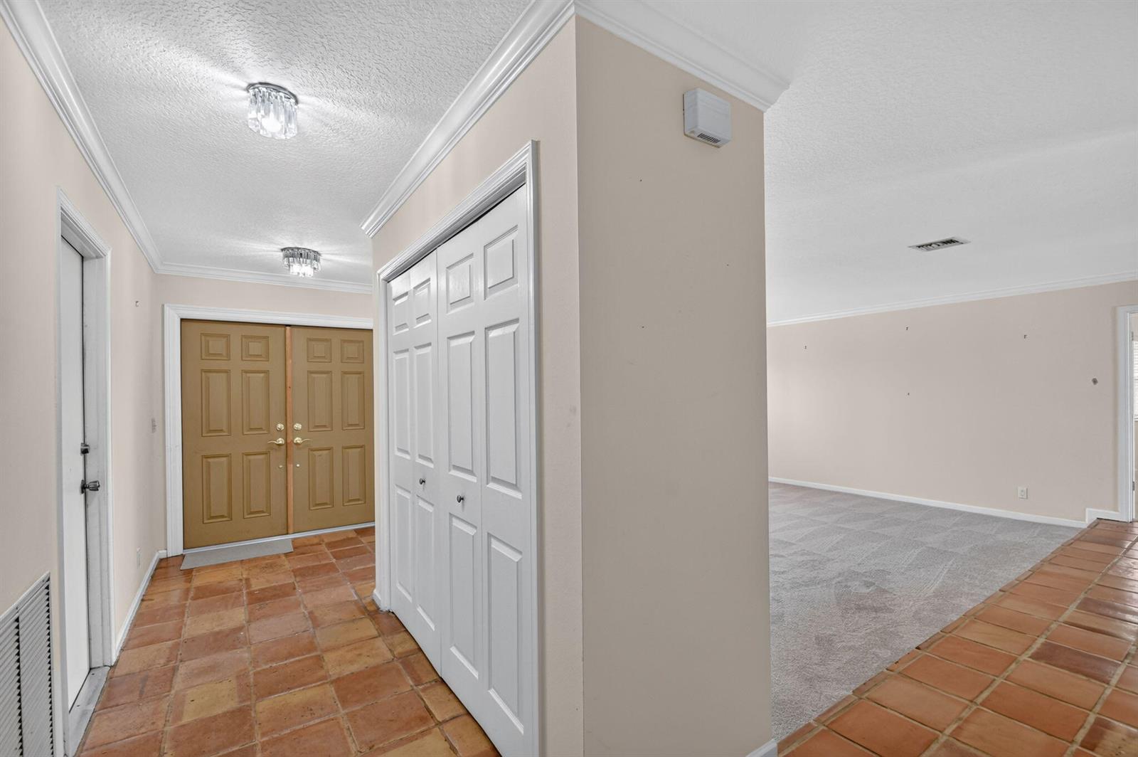 An entryway with terracotta tile floors leads to a carpeted living area and a closet — 2400 SW 23rd Cranbrook Drive, Boynton Beach FL 33436, BOYNTON BEACH, FL