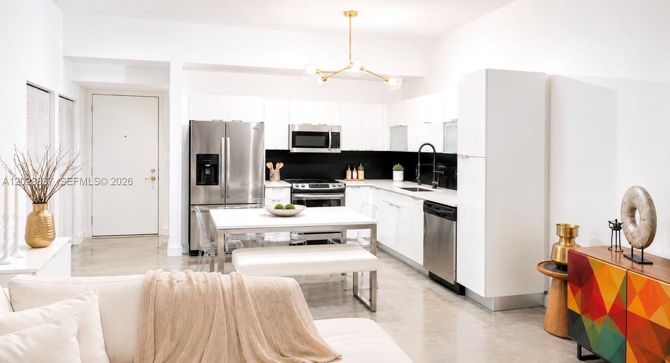 A modern kitchen features white cabinetry, stainless steel appliances, and a central dining table — 133 NE 2nd Ave # 2508, Miami FL 33132, MIAMI, FL