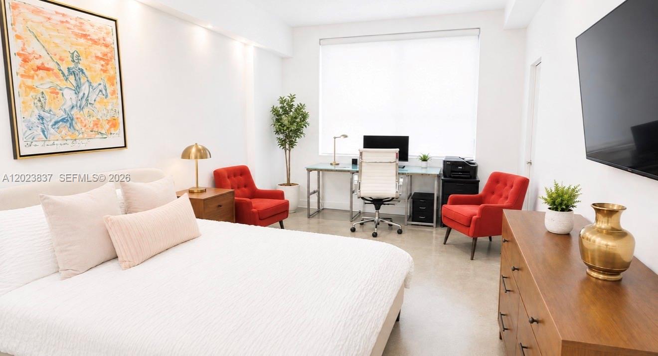 A bedroom features a bed, two red armchairs, a desk, and a wall-mounted television — 133 NE 2nd Ave # 2508, Miami FL 33132, MIAMI, FL