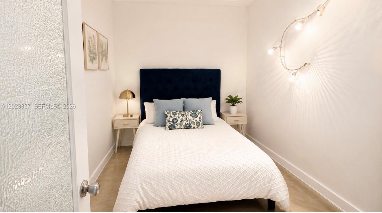 A bedroom features a blue tufted headboard, white bedding, and a curved wall light — 133 NE 2nd Ave # 2508, Miami FL 33132, MIAMI, FL