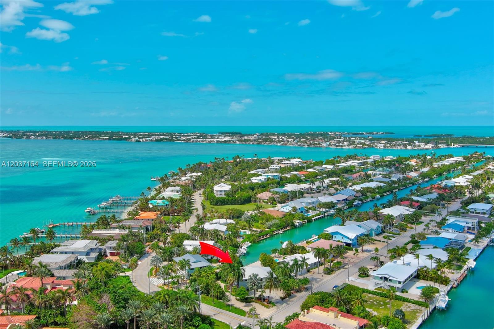 An aerial view shows a waterfront residential neighborhood with a red arrow pointing to a house — 181 12th St, Key Colony FL 33051, KEY COLONY, FL