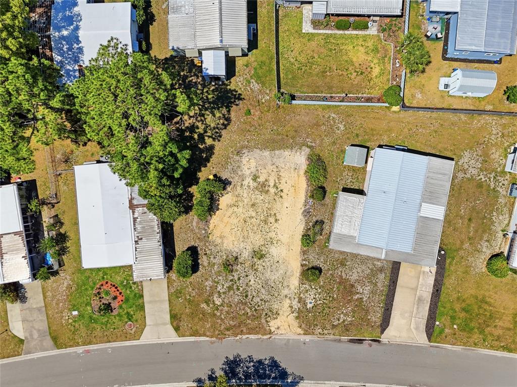 An aerial view shows a vacant residential lot situated between two existing mobile homes — 1223 NASSAU CIRCLE, TAVARES, FL