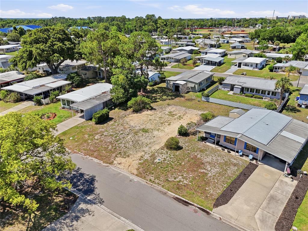 An aerial view shows a vacant residential lot situated between two manufactured homes on a street — 1223 NASSAU CIRCLE, TAVARES, FL