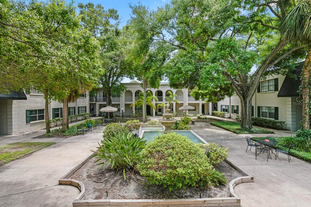 A courtyard with a central fountain, landscaping, and seating areas surrounded by apartment buildings — 4335 AEGEAN DRIVE UNIT 254A, TAMPA, FL