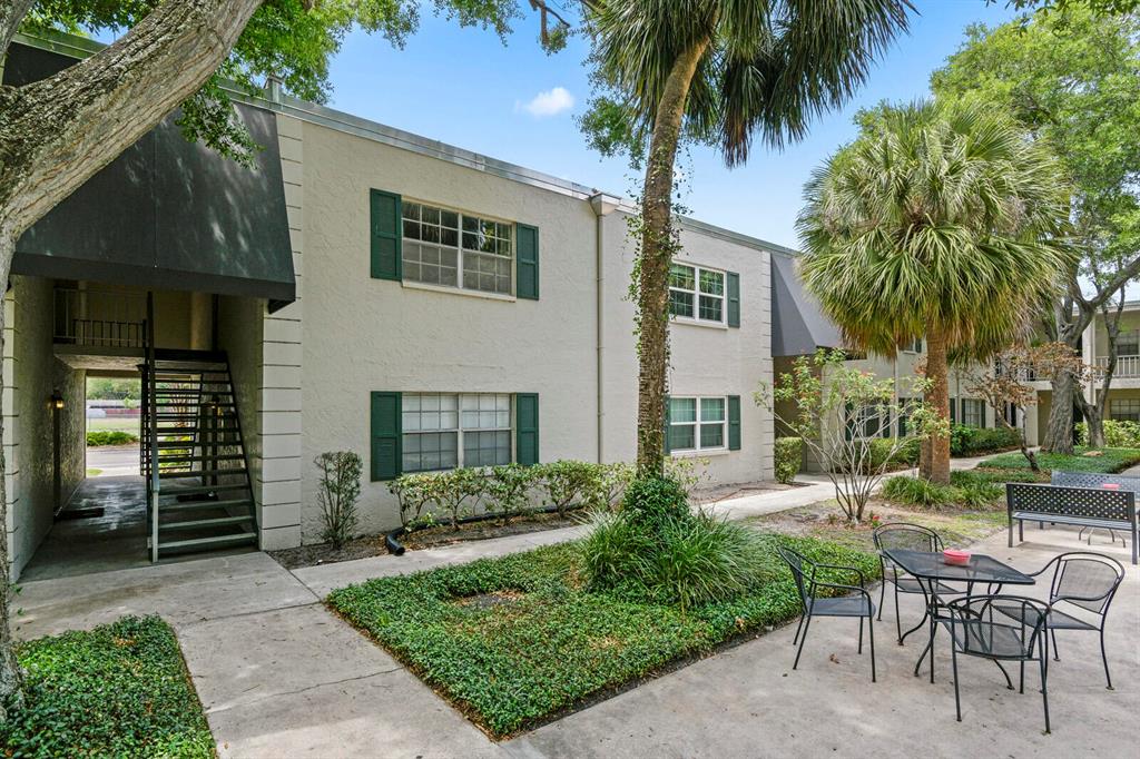 A two-story apartment building exterior features a staircase, green shutters, and a patio area — 4335 AEGEAN DRIVE UNIT 254A, TAMPA, FL