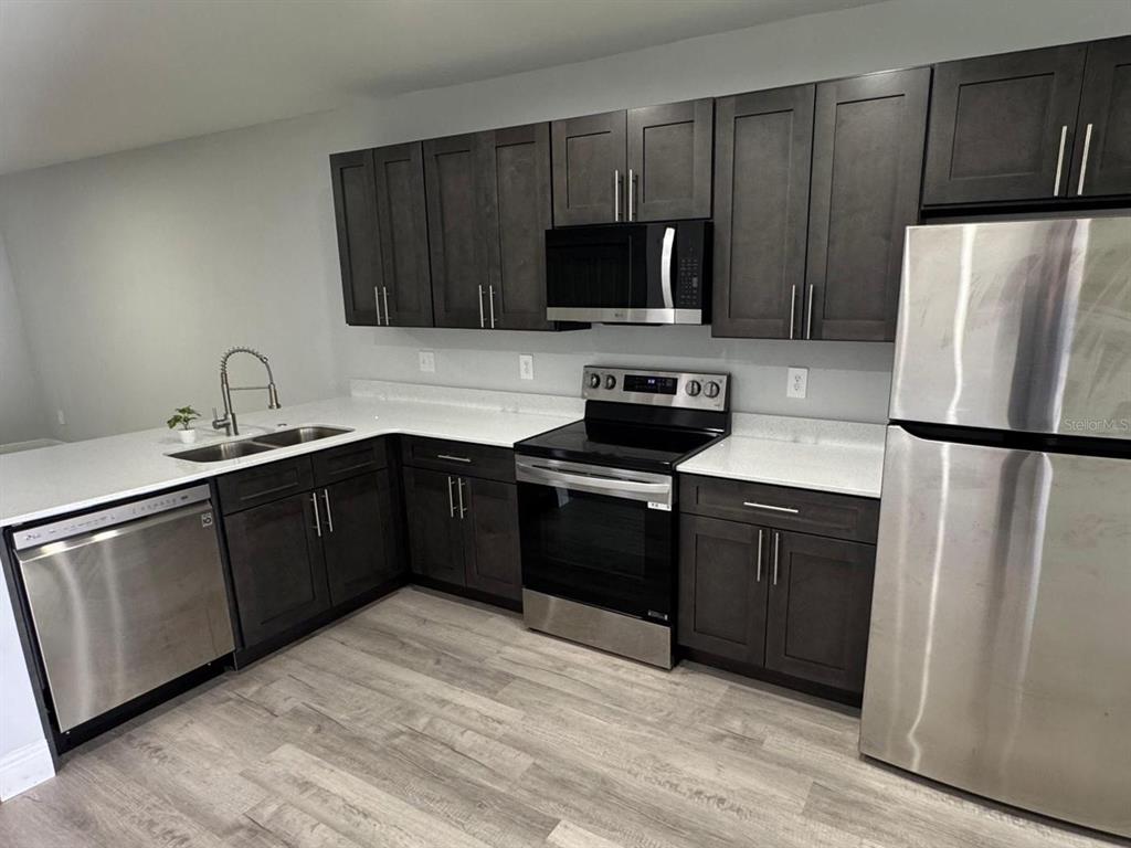A kitchen features dark wood cabinets, stainless steel appliances, and white countertops — 4508 LAFAYETTE AVENUE UNIT 4510, SEBRING, FL