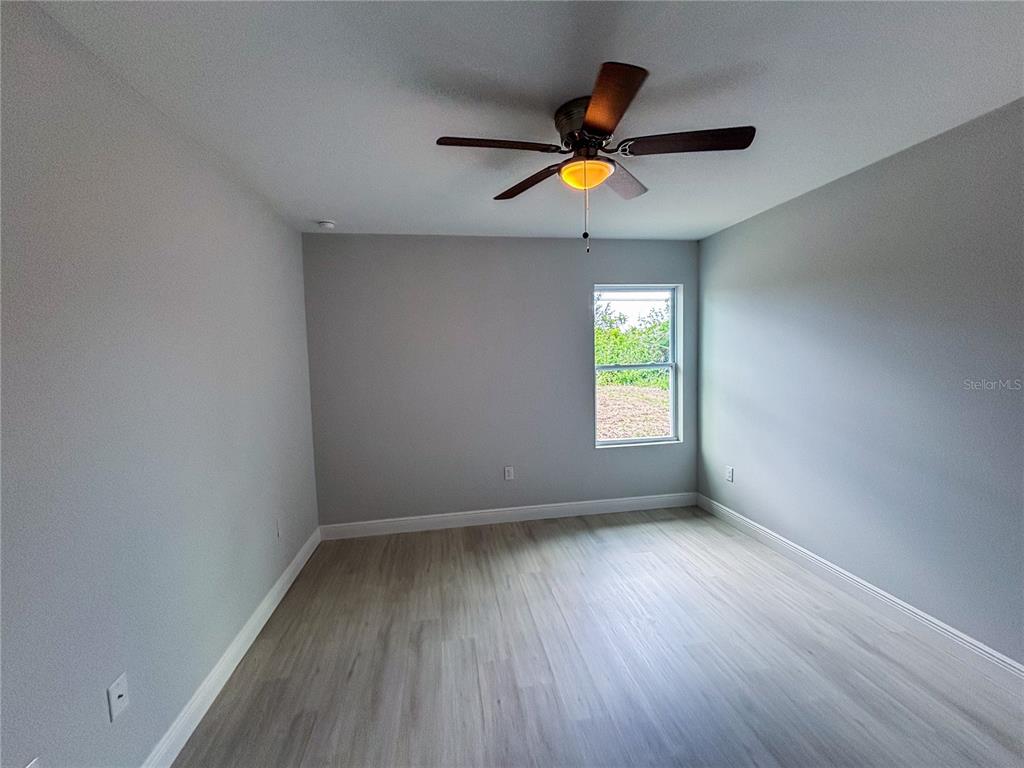 An empty bedroom features light gray walls, wood-look flooring, and a ceiling fan — 4508 LAFAYETTE AVENUE UNIT 4510, SEBRING, FL