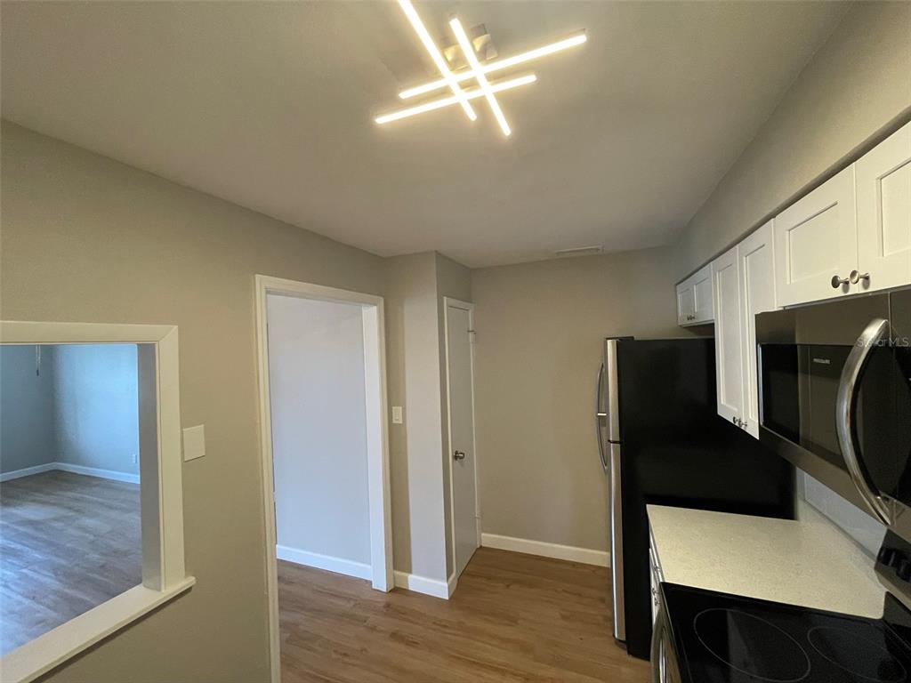 A kitchen features white cabinets, black appliances, light countertops, and a modern geometric ceiling light — 511 DUCHESS COURT UNIT 1, LAKELAND, FL