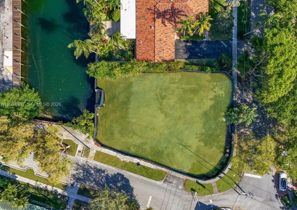 An aerial view shows a vacant, fenced-in residential lot situated next to a canal — 1805 Ixora Rd, North Miami FL 33181, NORTH MIAMI, FL