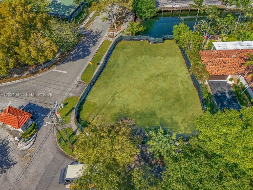 An aerial view shows a vacant, fenced-in rectangular lot situated between a road and a canal — 1805 Ixora Rd, North Miami FL 33181, NORTH MIAMI, FL