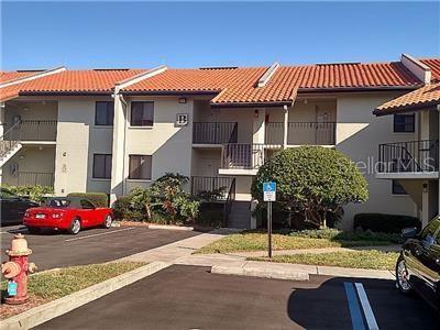 A two-story apartment building with a red tile roof and a red car parked outside — 1515 PINELLAS BAYWAY S UNIT 17, ST PETERSBURG, FL