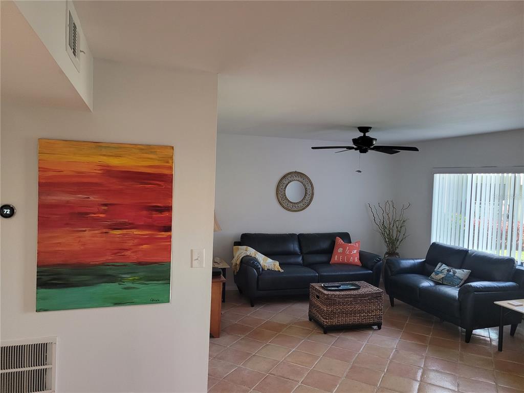A living room features two black leather sofas, a wicker coffee table, and tile flooring — 1515 PINELLAS BAYWAY S UNIT 17, ST PETERSBURG, FL