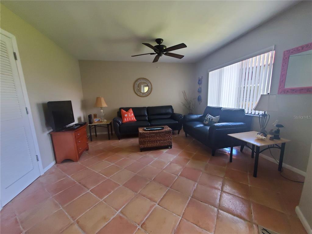 A living room features tile flooring, two black leather sofas, and a ceiling fan — 1515 PINELLAS BAYWAY S UNIT 17, ST PETERSBURG, FL