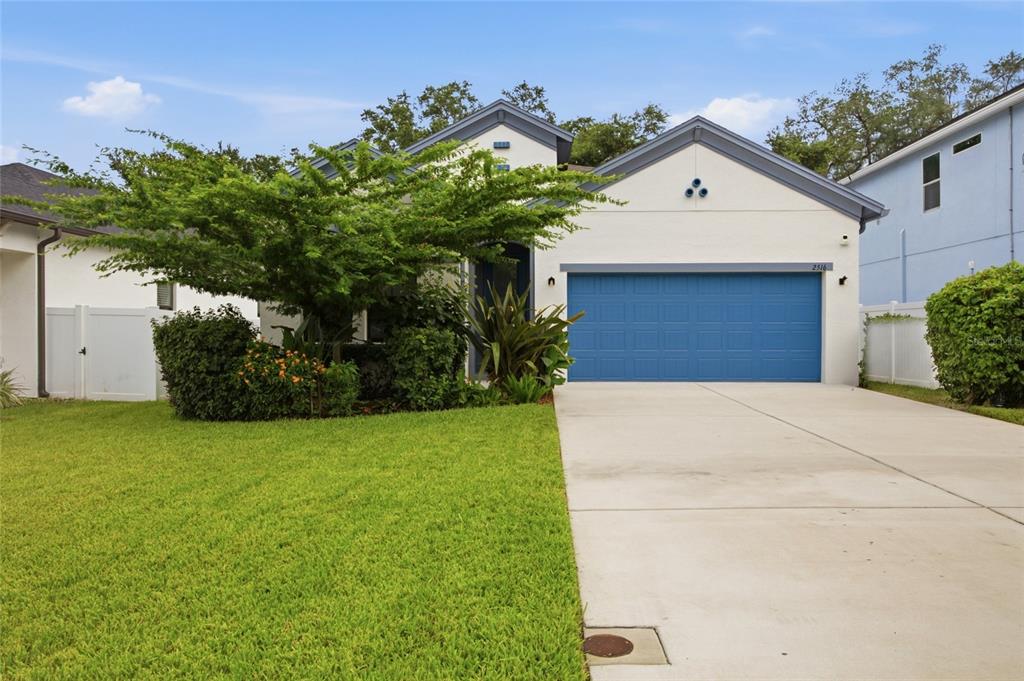 A single-story house with a white stucco exterior, blue garage door, and a front lawn — 2516 W CURTIS STREET, TAMPA, FL