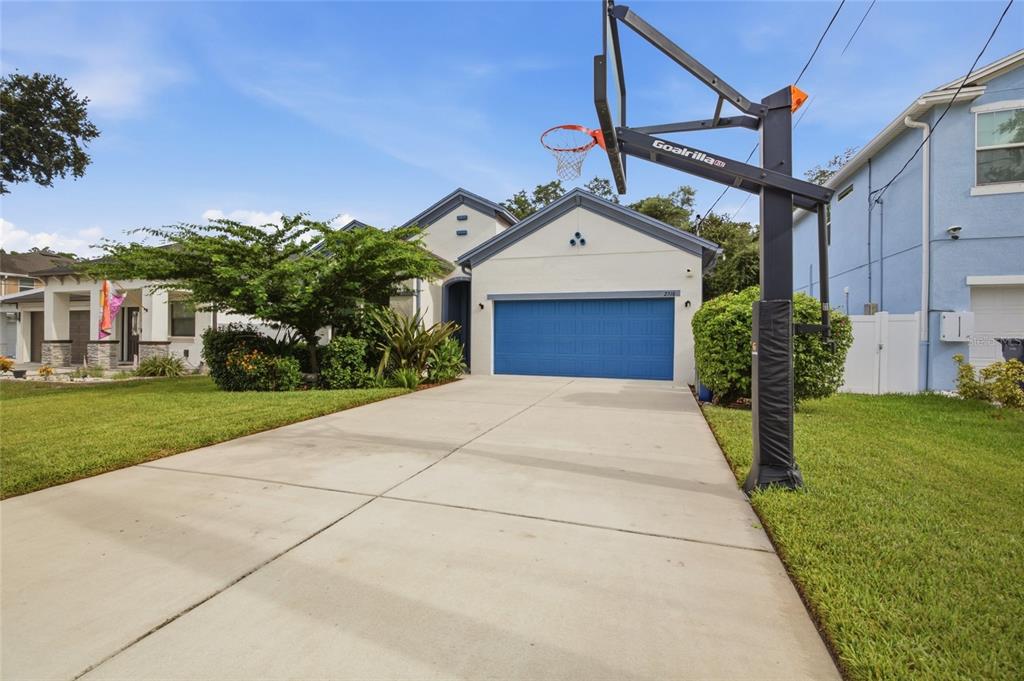A single-story house with a blue garage door and a basketball hoop in the driveway — 2516 W CURTIS STREET, TAMPA, FL