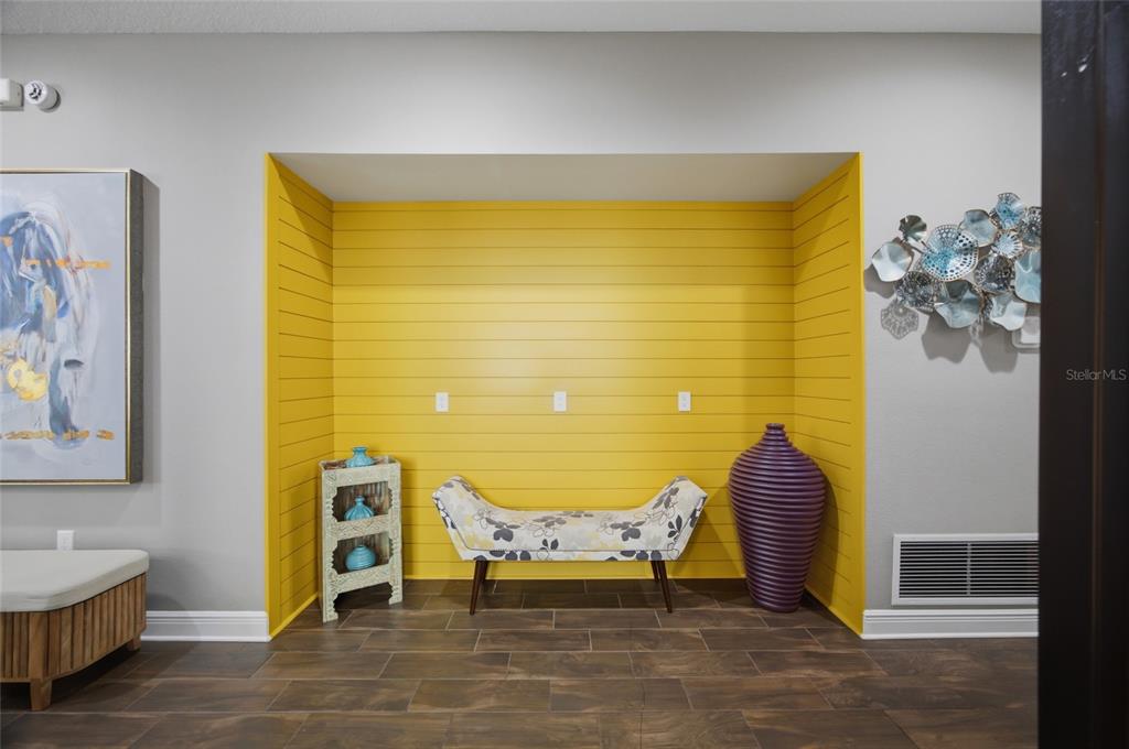 A recessed alcove with yellow shiplap walls features a patterned bench, side table, and vase — 2516 W CURTIS STREET, TAMPA, FL