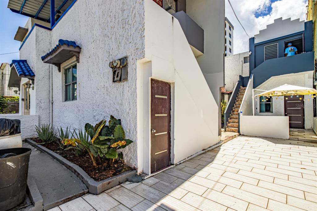 A white building exterior with a brown door, tiled patio, and an outdoor staircase — 1 PLACID COURT UNIT 71, SAN JUAN, PR