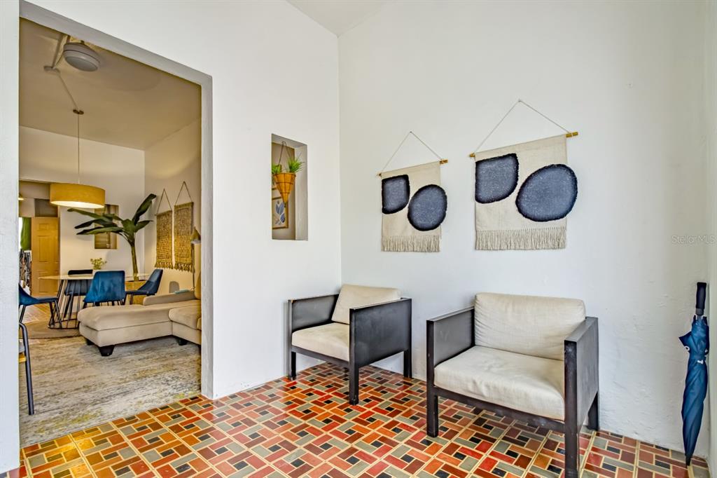 A covered porch features two armchairs, patterned tile flooring, and wall-mounted textile art — 1 PLACID COURT UNIT 71, SAN JUAN, PR