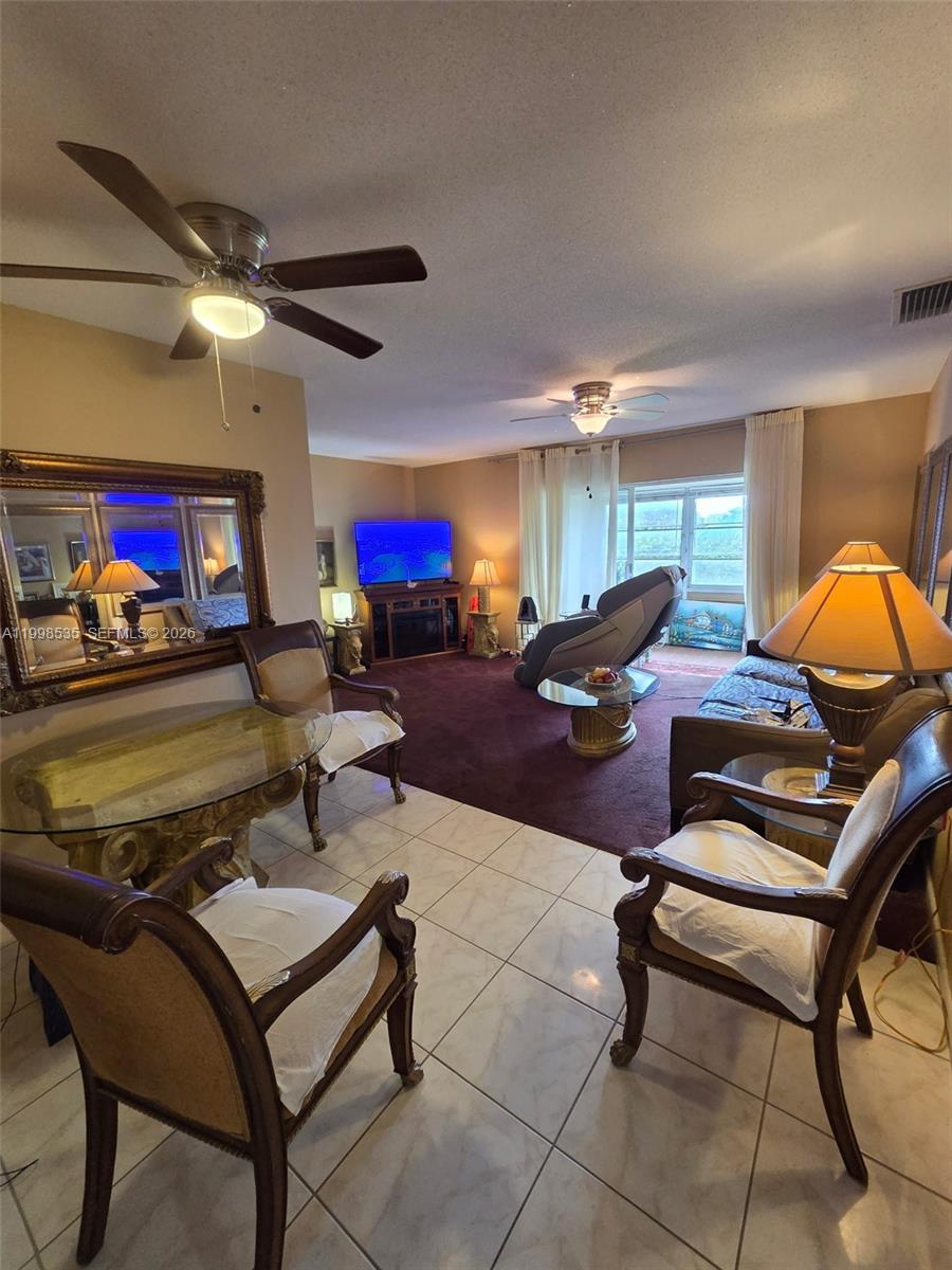A living and dining area features tile floors, a dark rug, and two ceiling fans — 410 NE 17th Ave # 203, Boynton Beach FL 33435, BOYNTON BEACH, FL