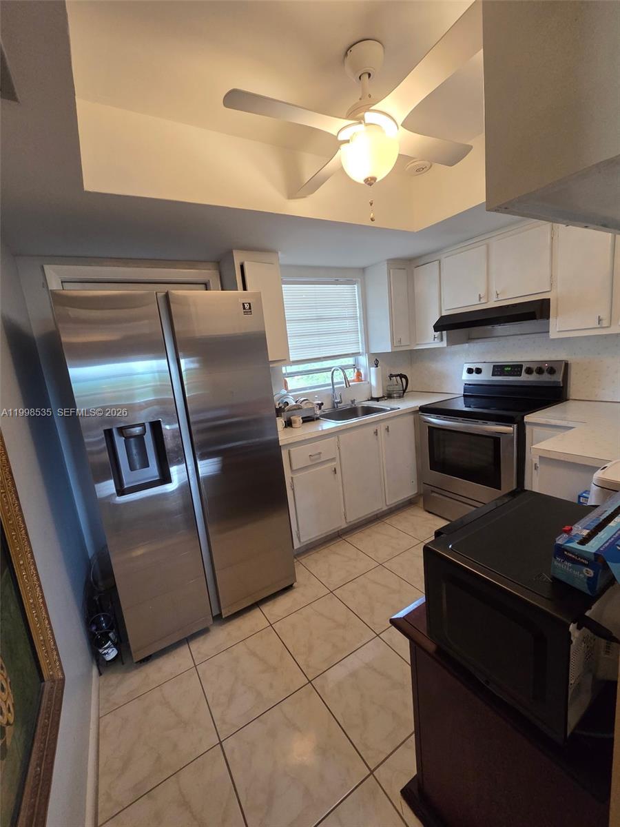 A kitchen features white cabinets, stainless steel appliances, a ceiling fan, and light-colored tile flooring — 410 NE 17th Ave # 203, Boynton Beach FL 33435, BOYNTON BEACH, FL