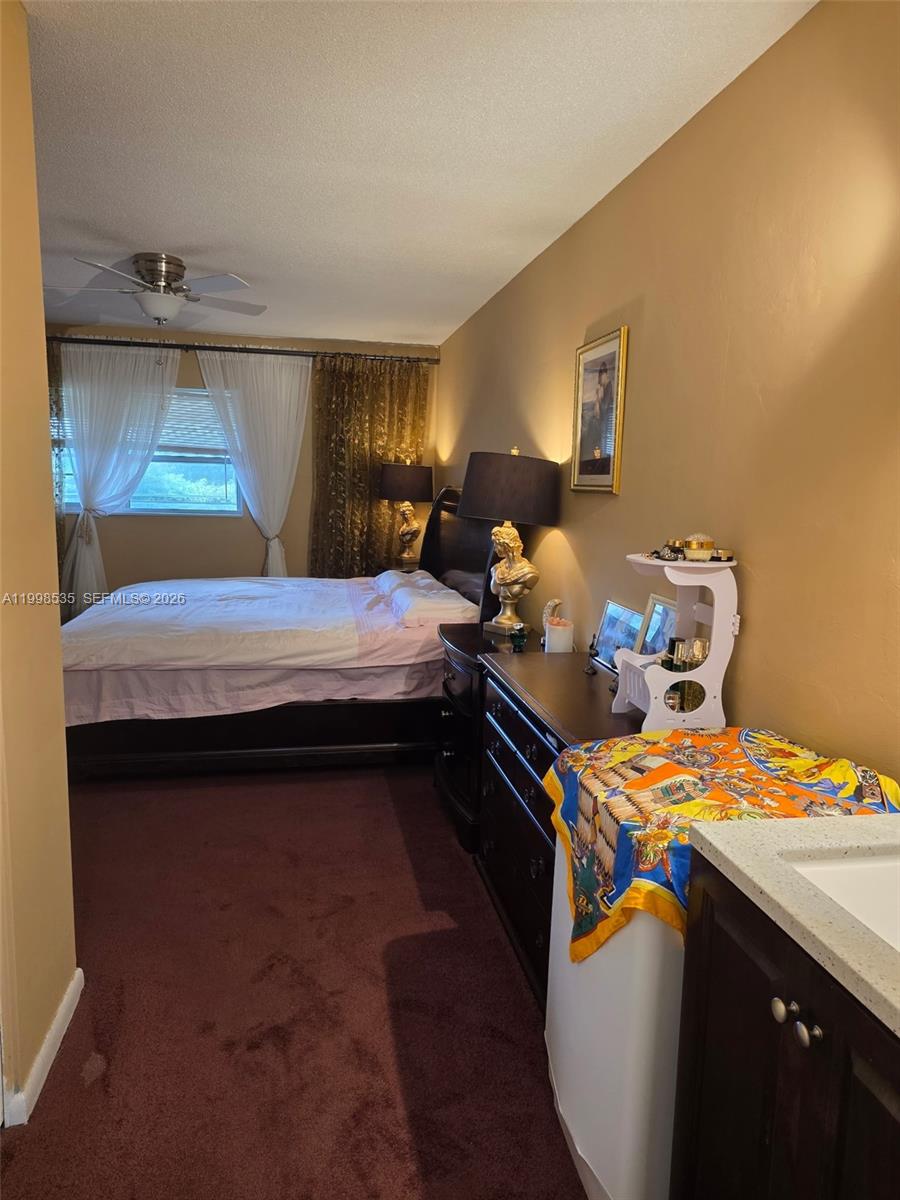 A bedroom features dark wood furniture, a bed with white bedding, and a vanity area — 410 NE 17th Ave # 203, Boynton Beach FL 33435, BOYNTON BEACH, FL