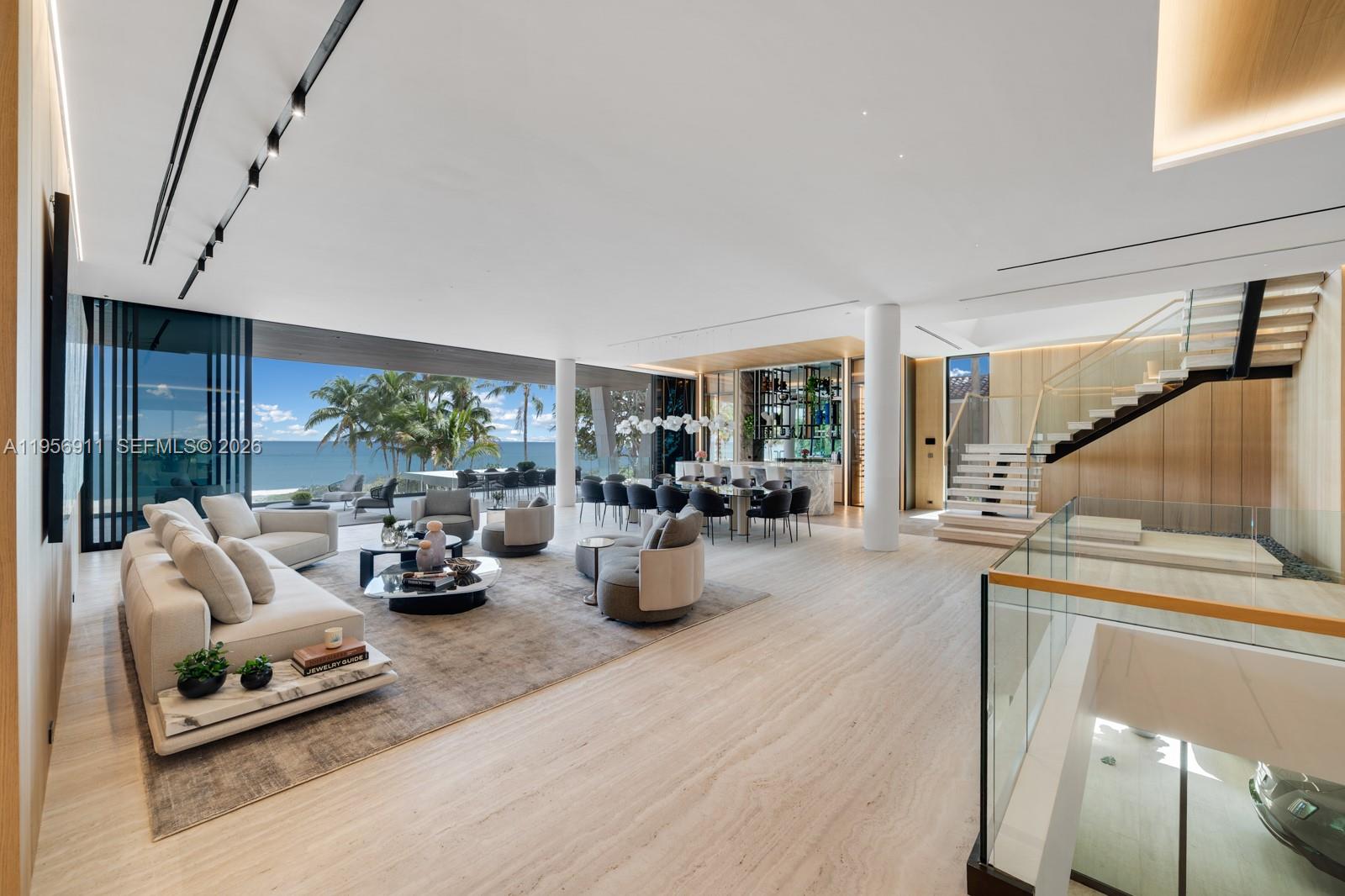 A spacious, modern living area with ocean views, marble floors, and a floating staircase — 255 Ocean Blvd, Golden Beach FL 33160, GOLDEN BEACH, FL