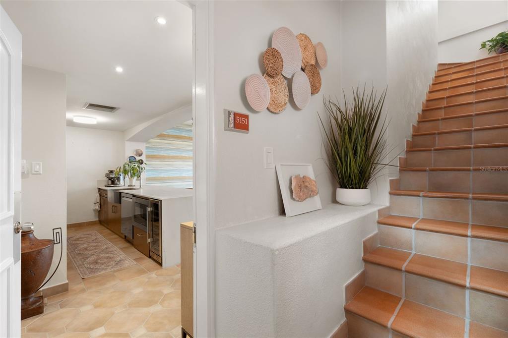 A tiled staircase leads upward next to a kitchen with a white island and counter — 1000 AVENUE EL CONQUISTADOR UNIT 5151, FAJARDO, PR