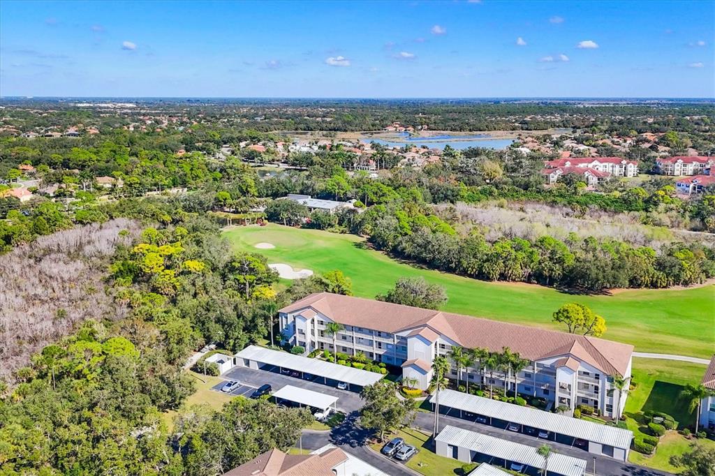 An aerial view of a multi-story apartment building adjacent to a golf course — 8735 OLDE HICKORY AVENUE UNIT 8303, SARASOTA, FL