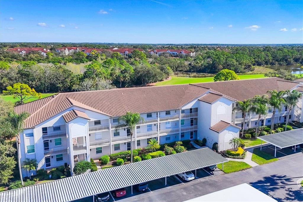 An aerial view of a multi-story apartment building with a covered parking area — 8735 OLDE HICKORY AVENUE UNIT 8303, SARASOTA, FL