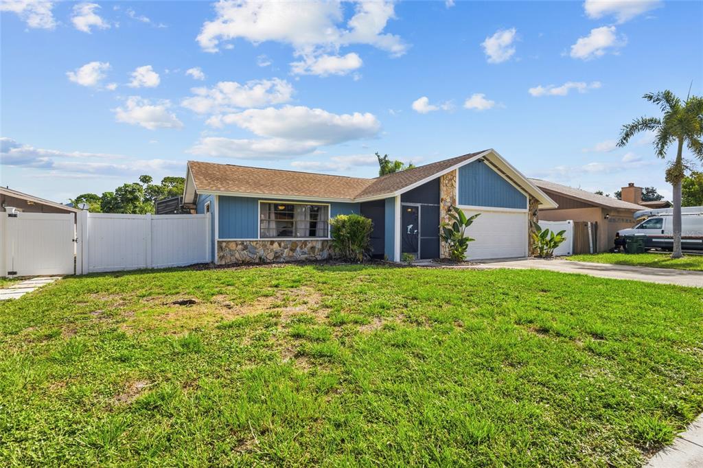 A single-story house with blue siding, stone accents, and a white vinyl fence — 6535 JARVIS ROAD, SARASOTA, FL