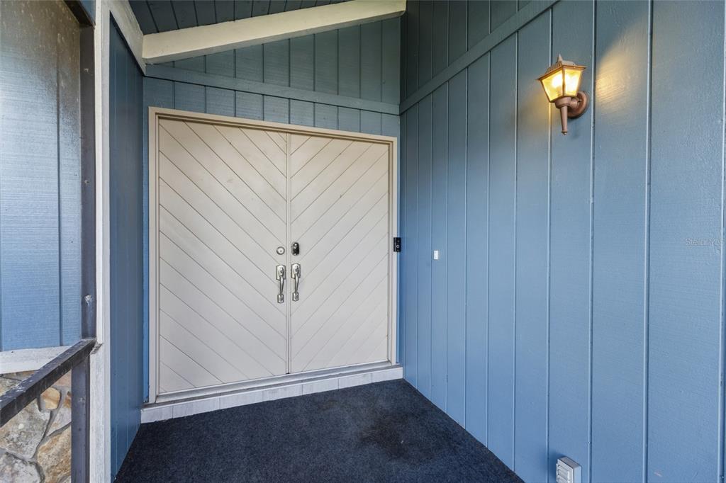 A blue-sided exterior entryway features double doors with a diagonal wood pattern and a light — 6535 JARVIS ROAD, SARASOTA, FL