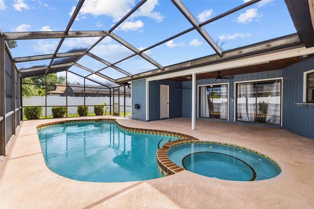 A screened-in patio features a swimming pool, a circular spa, and blue exterior walls — 6535 JARVIS ROAD, SARASOTA, FL