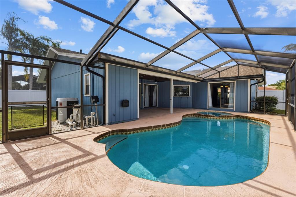 A backyard swimming pool with a spa is enclosed by a screened lanai — 6535 JARVIS ROAD, SARASOTA, FL