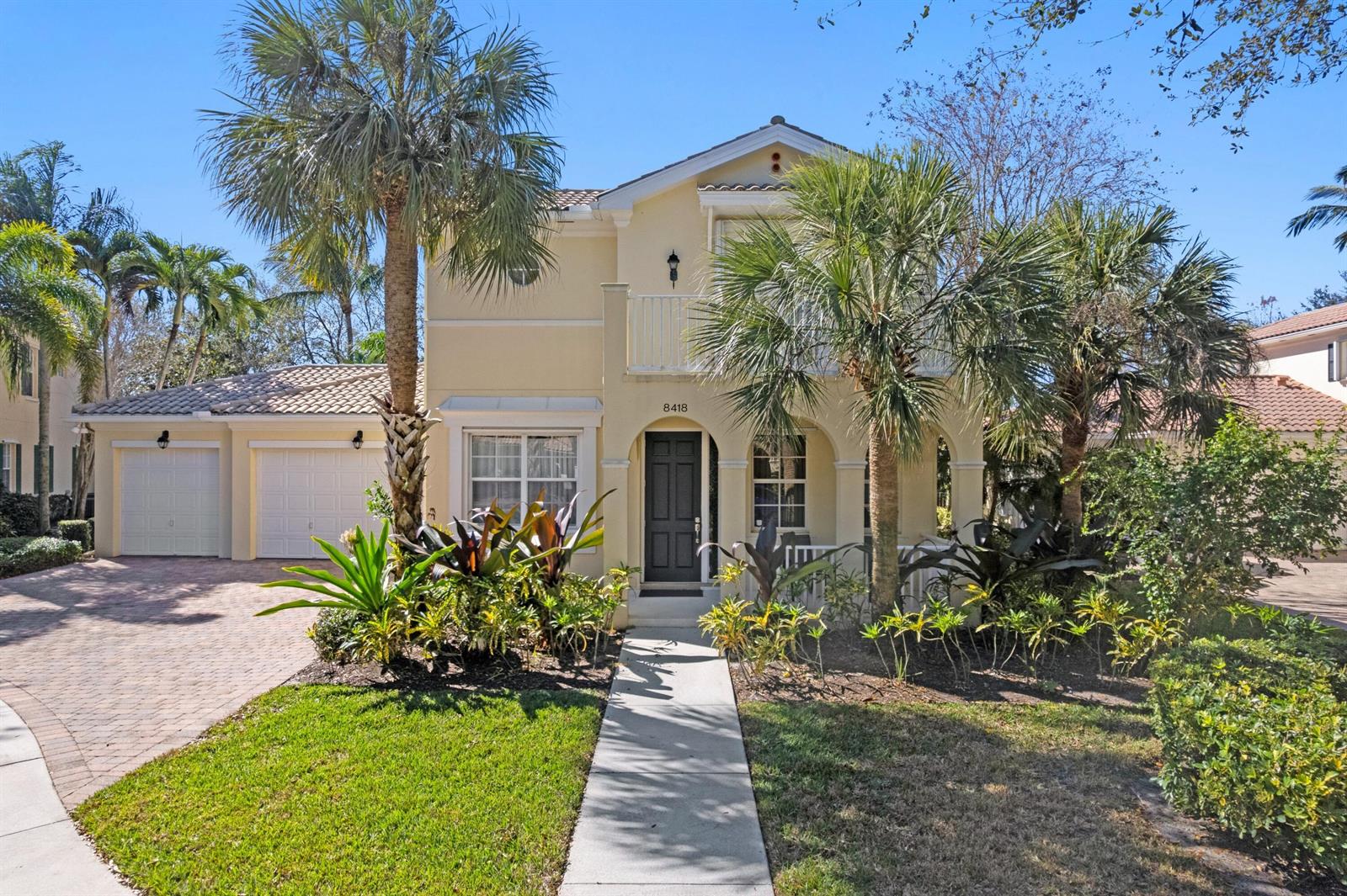 A two-story yellow stucco house with a tile roof, palm trees, and a paved driveway — 8418 Arima Lane, Wellington FL 33414, WELLINGTON, FL