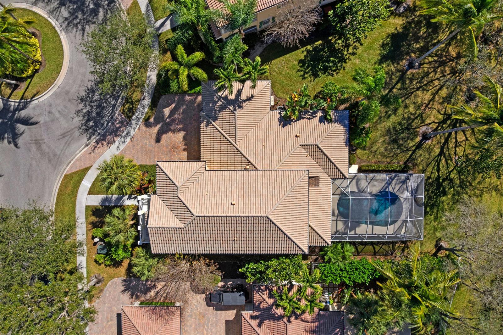 An aerial view of a house with a tiled roof, a screened pool, and paved driveway — 8418 Arima Lane, Wellington FL 33414, WELLINGTON, FL