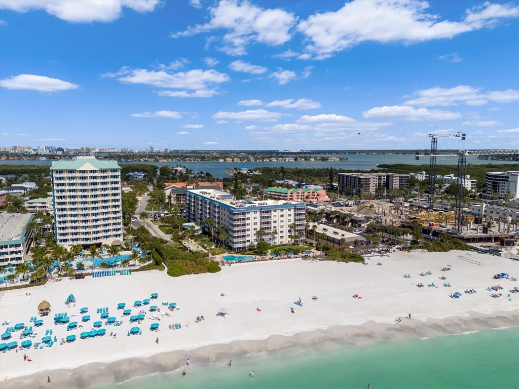 An aerial view shows a white sand beach, resort buildings, and a construction site — 800 BENJAMIN FRANKLIN DRIVE UNIT 505, SARASOTA, FL