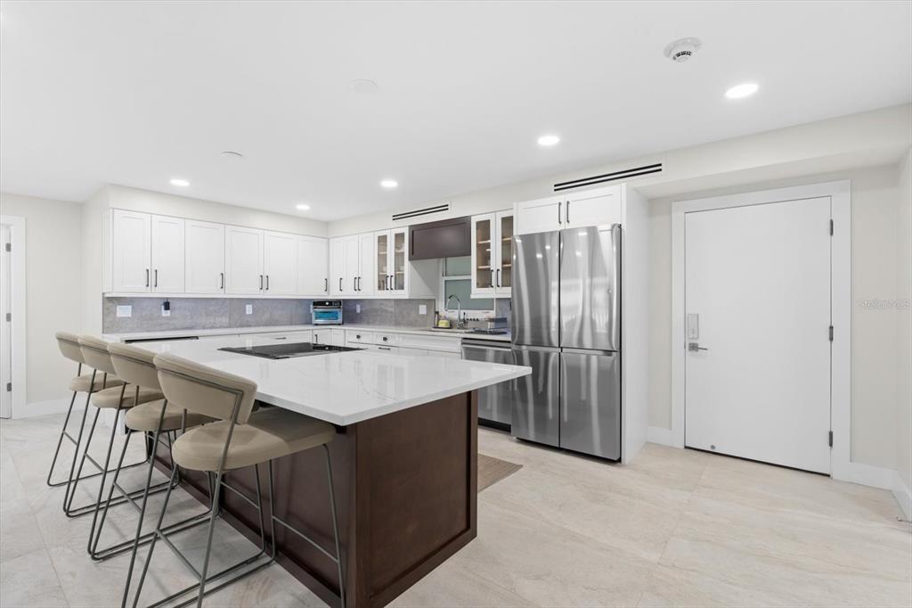 A modern kitchen features white cabinetry, a dark wood island, and stainless steel appliances — 800 BENJAMIN FRANKLIN DRIVE UNIT 505, SARASOTA, FL