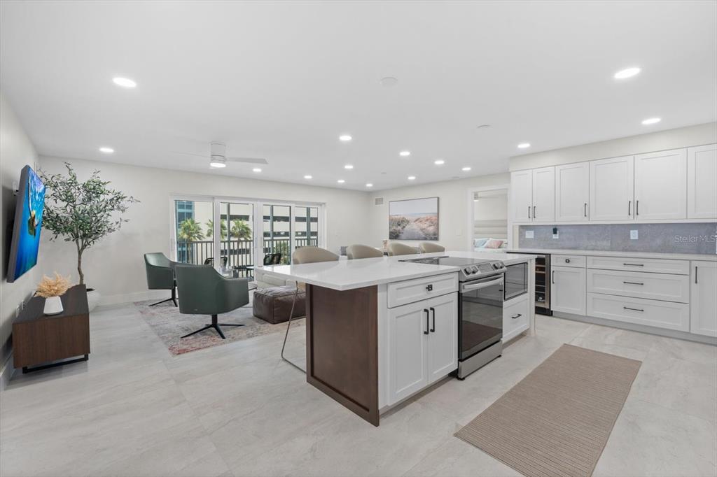 A modern kitchen with a white island and stainless steel appliances opens to a living area — 800 BENJAMIN FRANKLIN DRIVE UNIT 505, SARASOTA, FL