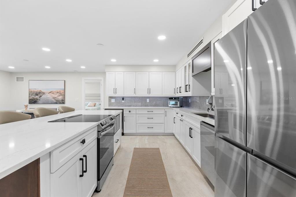 A modern kitchen features white cabinetry, stainless steel appliances, and a large quartz-topped island — 800 BENJAMIN FRANKLIN DRIVE UNIT 505, SARASOTA, FL