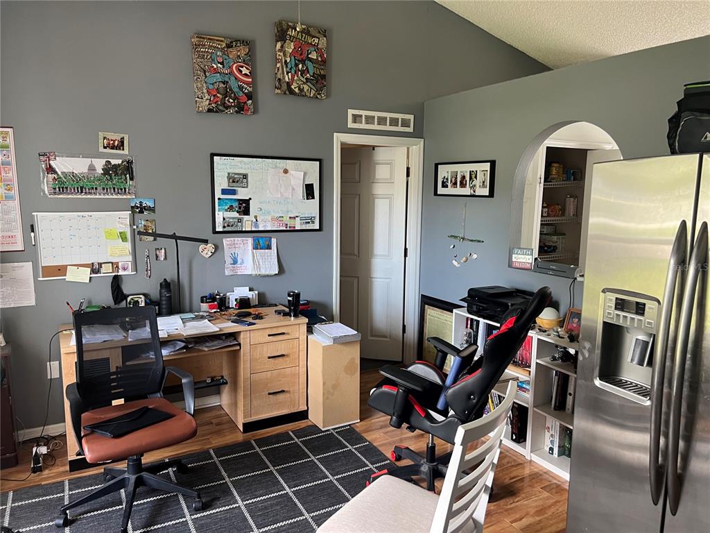 A home office features a desk, two rolling chairs, a whiteboard, and a nearby refrigerator — 69 RAEMOOR DRIVE, PALM COAST, FL