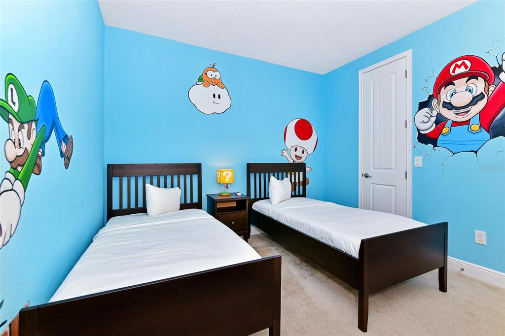 A bedroom with two twin beds, dark wood frames, and Super Mario wall decals — 7705 BANYON WAY, KISSIMMEE, FL