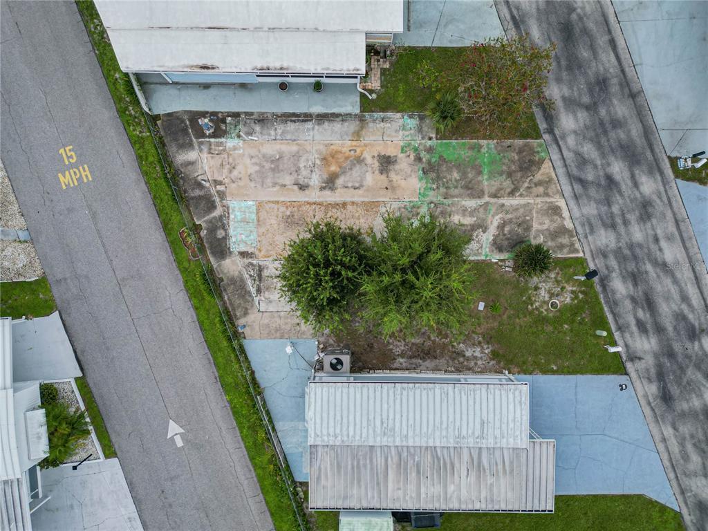 An aerial view shows a concrete pad between two mobile homes with trees and landscaping — 7066 FAIRVIEW VILLAGE CIRCLE, WINTER HAVEN, FL
