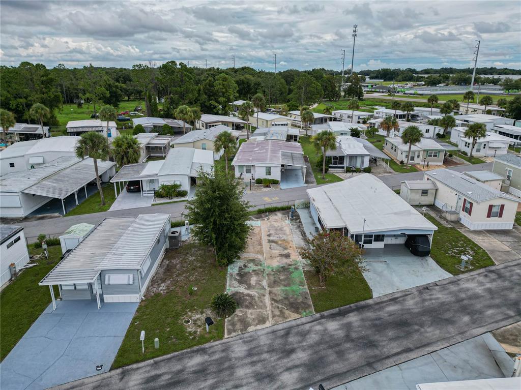 An aerial view shows a vacant residential lot situated between two manufactured homes in a community — 7066 FAIRVIEW VILLAGE CIRCLE, WINTER HAVEN, FL