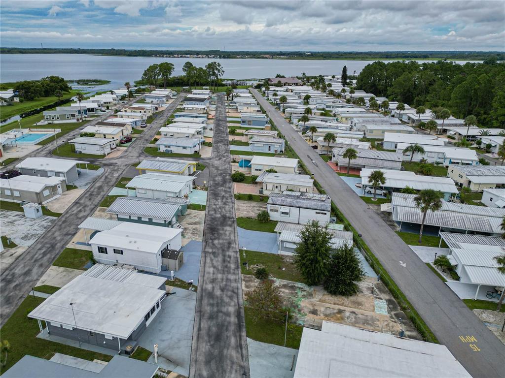 An aerial view shows a mobile home park with rows of houses near a lake — 7066 FAIRVIEW VILLAGE CIRCLE, WINTER HAVEN, FL