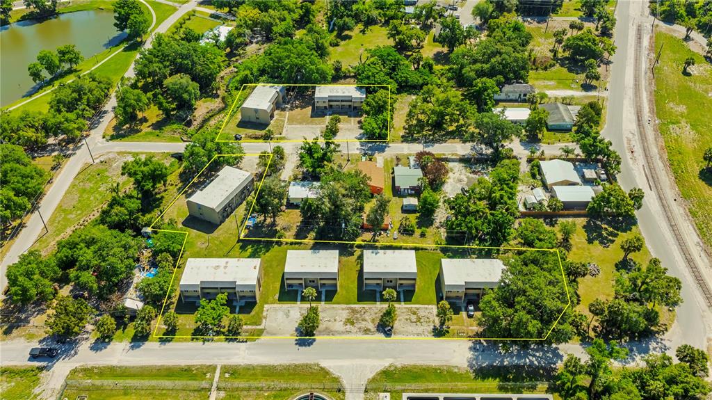 This aerial view shows several multi-family residential buildings situated on a lot with trees — 111 JORDAN AVENUE, ARCADIA, FL